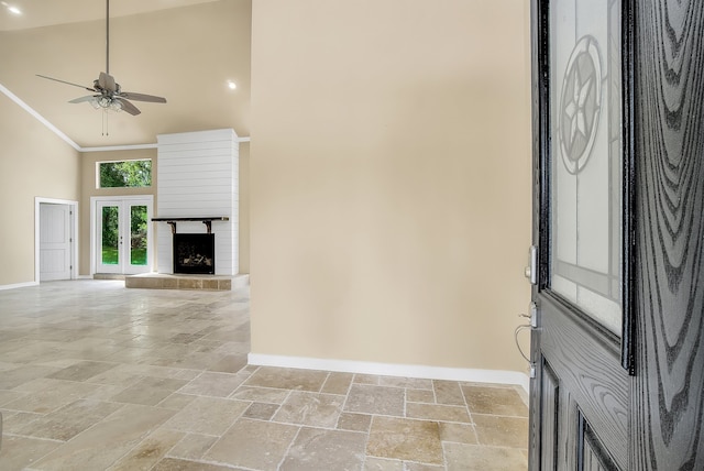 entrance foyer featuring high vaulted ceiling, ceiling fan, crown molding, light tile flooring, and a tile fireplace