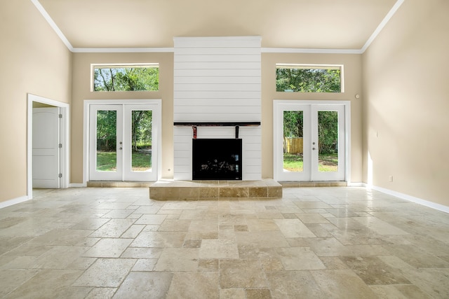 unfurnished living room with french doors, crown molding, light tile flooring, and a high ceiling