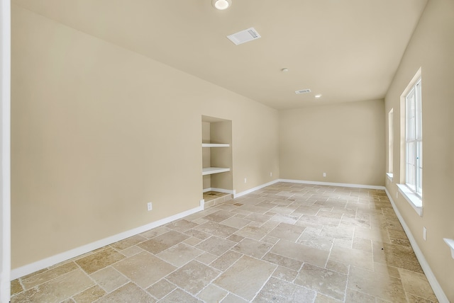 empty room with light tile floors and built in shelves