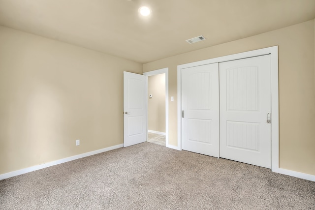 unfurnished bedroom featuring light colored carpet and a closet