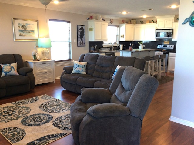 living room with ornamental molding, dark hardwood / wood-style flooring, sink, and ceiling fan