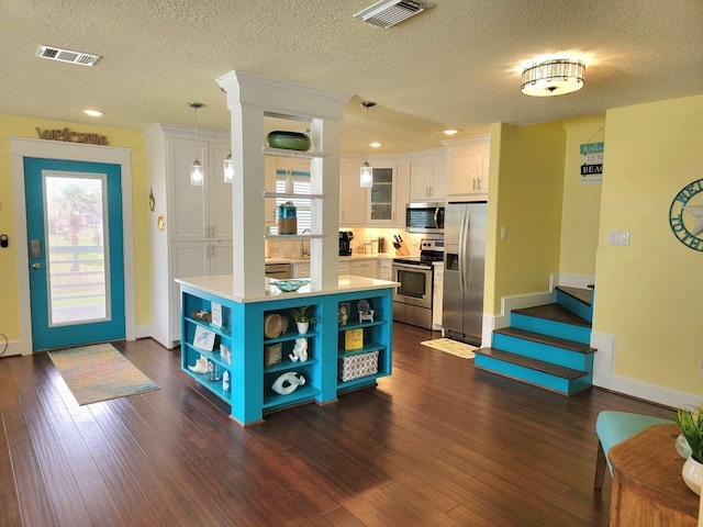 kitchen with a center island, dark hardwood / wood-style floors, appliances with stainless steel finishes, decorative light fixtures, and white cabinetry