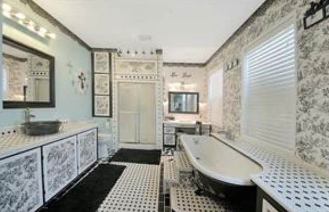 bathroom featuring a bath, vanity, and tile floors