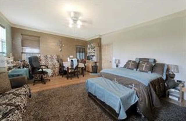 bedroom with crown molding, dark wood-type flooring, and ceiling fan