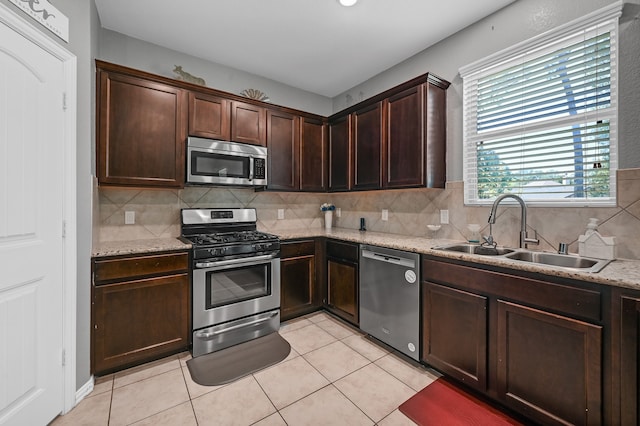 kitchen with backsplash, appliances with stainless steel finishes, light tile floors, and sink