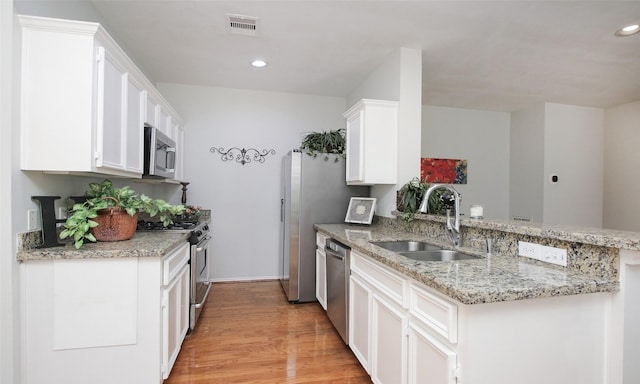 kitchen featuring appliances with stainless steel finishes, kitchen peninsula, sink, and white cabinets