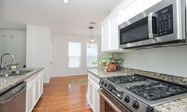 kitchen featuring stainless steel appliances, light stone countertops, sink, and white cabinets