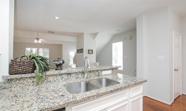 kitchen featuring white cabinetry, light stone countertops, and sink