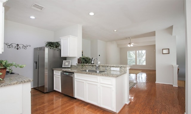 kitchen with dishwasher, sink, white cabinets, kitchen peninsula, and light stone countertops