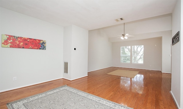 empty room with lofted ceiling, hardwood / wood-style floors, and ceiling fan