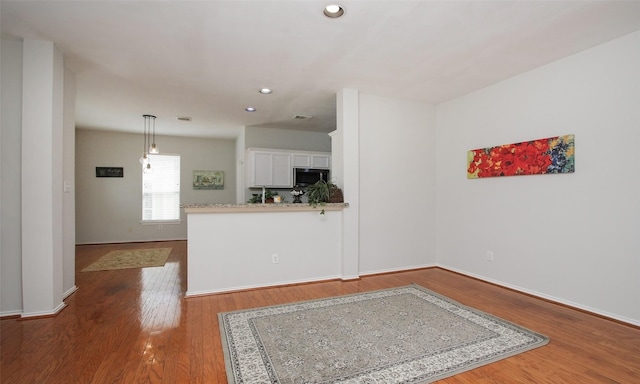 kitchen with wood-type flooring, pendant lighting, white cabinets, and kitchen peninsula