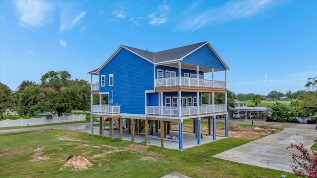 rear view of property featuring a balcony, a carport, and a lawn