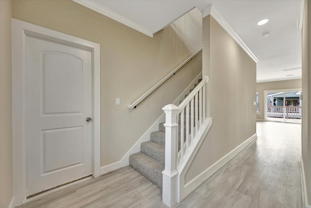 stairway with crown molding and hardwood / wood-style floors