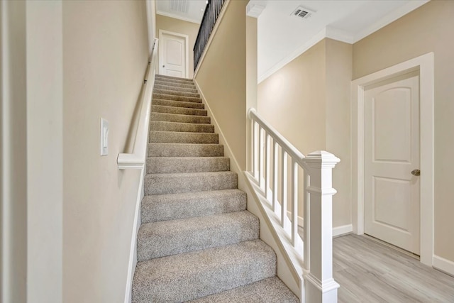 stairs with ornamental molding and hardwood / wood-style flooring