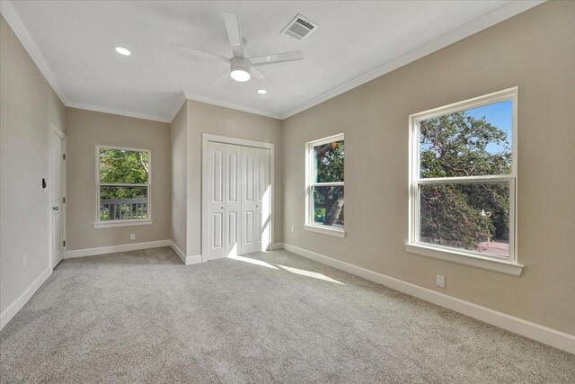 unfurnished bedroom with ornamental molding, a closet, ceiling fan, and light colored carpet