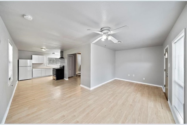 unfurnished living room featuring a wealth of natural light, light hardwood / wood-style floors, and ceiling fan