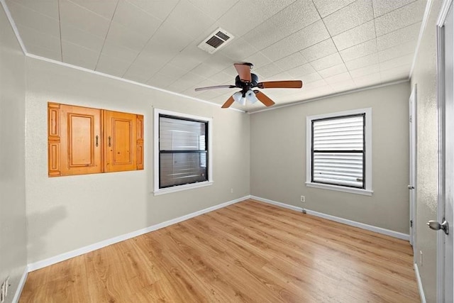 empty room with ceiling fan, ornamental molding, and light wood-type flooring