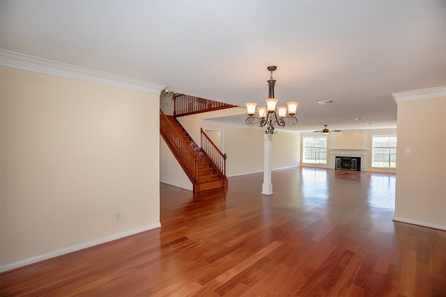 unfurnished living room with crown molding, ceiling fan with notable chandelier, and dark wood-type flooring