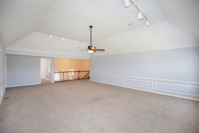 unfurnished living room with light colored carpet, vaulted ceiling, ceiling fan, rail lighting, and ornamental molding