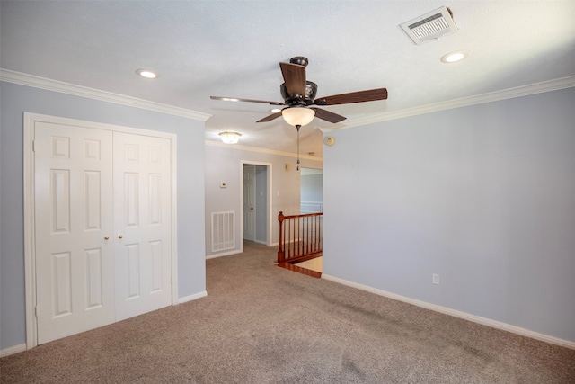 unfurnished bedroom with ornamental molding, carpet flooring, ceiling fan, and a closet