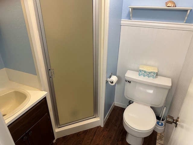 bathroom featuring wood-type flooring, vanity, an enclosed shower, and toilet