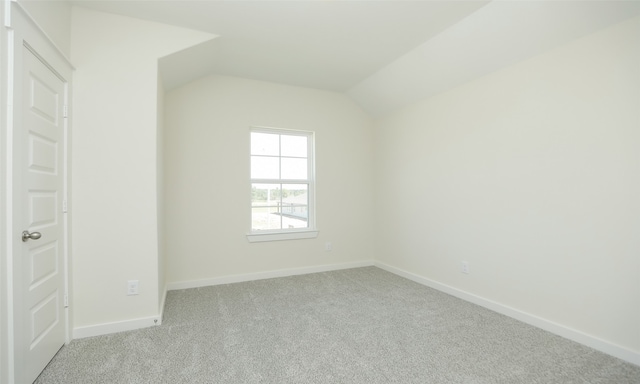 carpeted spare room with vaulted ceiling