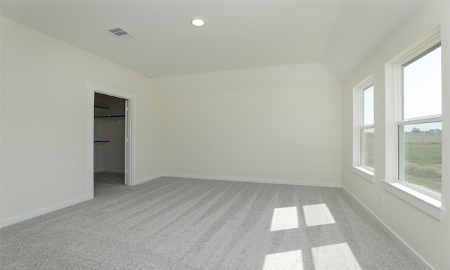 carpeted spare room featuring vaulted ceiling and a wealth of natural light