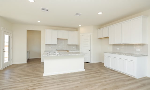 kitchen with light wood-type flooring, backsplash, and white cabinets