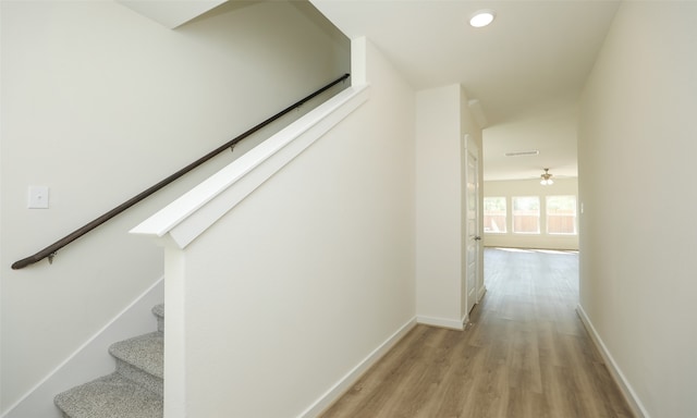 staircase featuring ceiling fan and hardwood / wood-style floors