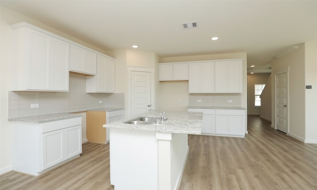 kitchen with white cabinets, a center island with sink, and sink