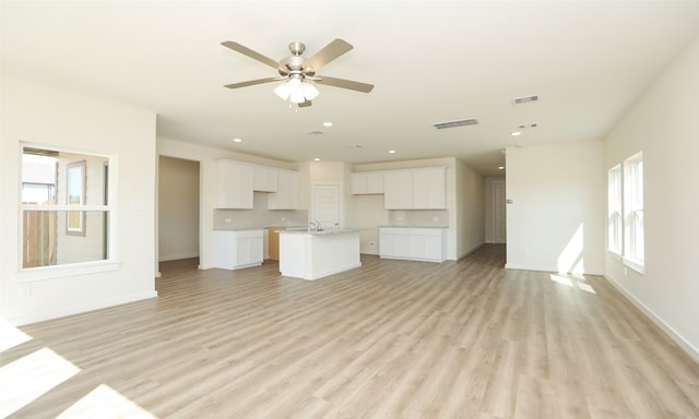 unfurnished living room featuring ceiling fan, a wealth of natural light, and light hardwood / wood-style floors