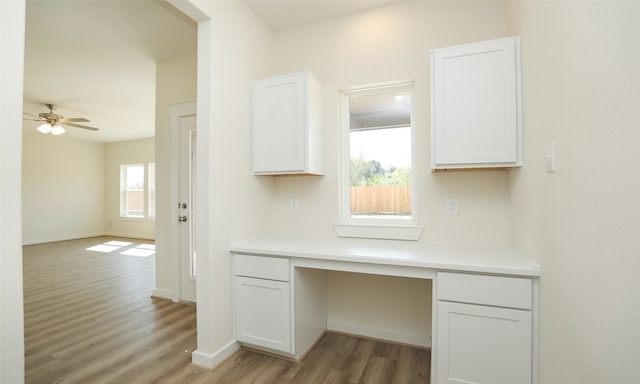 kitchen featuring built in desk, light hardwood / wood-style floors, white cabinetry, and a wealth of natural light