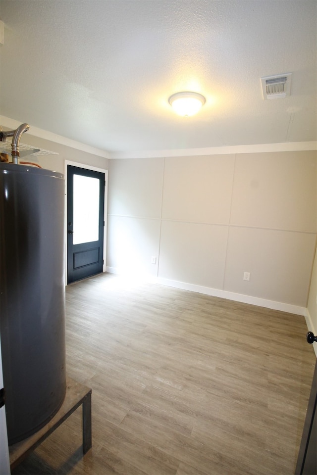 spare room with crown molding, water heater, and light wood-type flooring