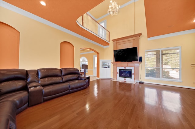 living room featuring ornamental molding, a notable chandelier, hardwood / wood-style flooring, and a tiled fireplace