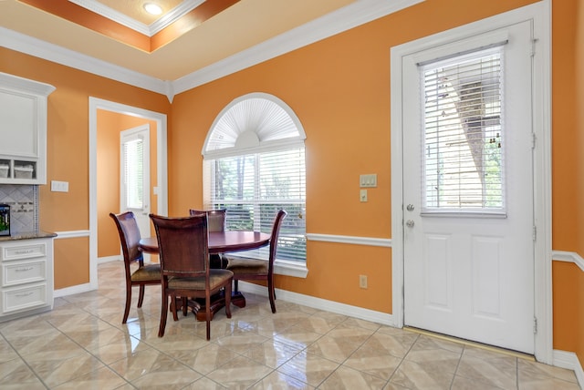 dining area featuring ornamental molding, light tile floors, and a tray ceiling