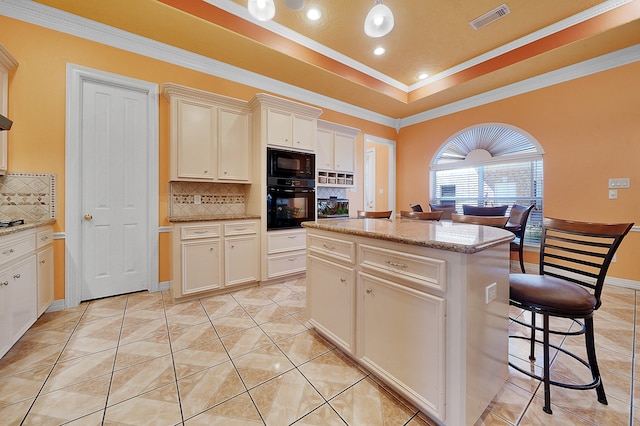 kitchen featuring tasteful backsplash, a center island, black appliances, and a tray ceiling