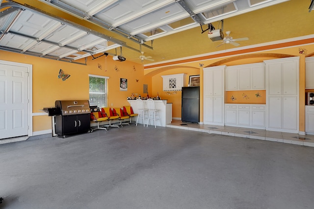 garage featuring black refrigerator, ceiling fan, and a garage door opener