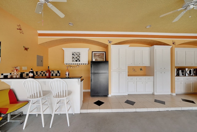 kitchen featuring white cabinetry, ceiling fan, black fridge, and light tile floors