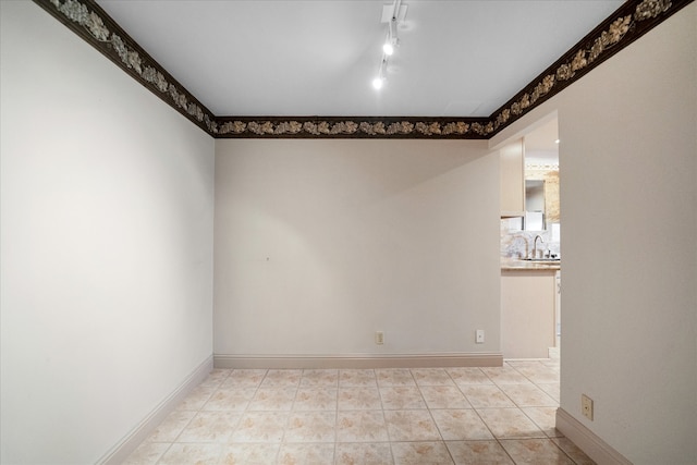 spare room with light tile patterned flooring, rail lighting, and sink