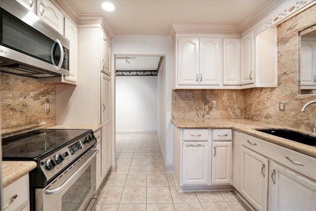 kitchen featuring appliances with stainless steel finishes, white cabinetry, sink, decorative backsplash, and light tile patterned floors