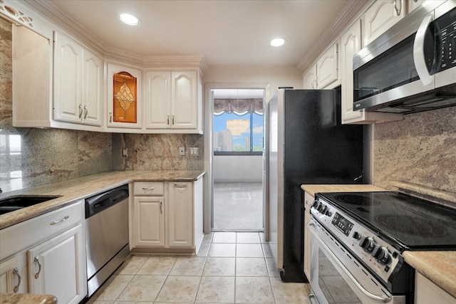 kitchen featuring light tile patterned flooring, appliances with stainless steel finishes, white cabinets, decorative backsplash, and light stone countertops