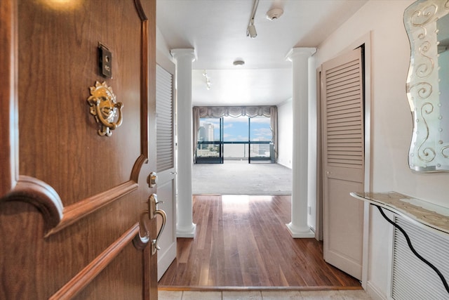 corridor with dark colored carpet, track lighting, and decorative columns