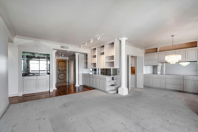 kitchen with hanging light fixtures, decorative columns, crown molding, rail lighting, and an inviting chandelier