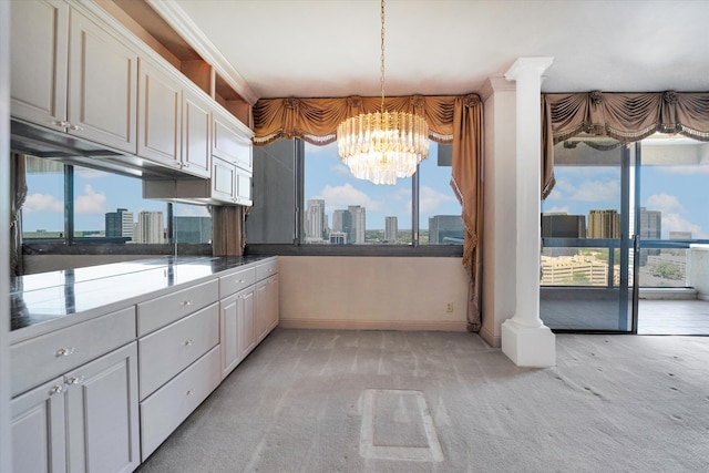 kitchen featuring an inviting chandelier, plenty of natural light, light colored carpet, and decorative columns