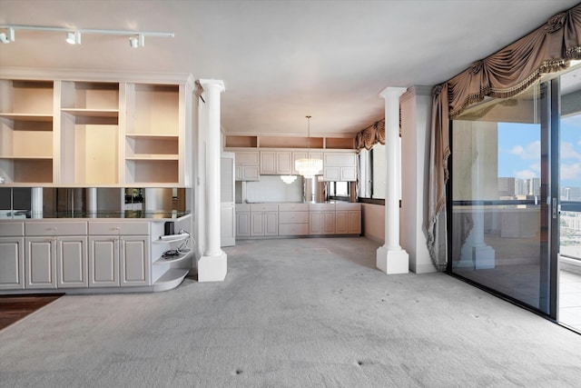 unfurnished living room featuring decorative columns and carpet flooring