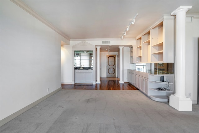 interior space featuring plenty of natural light, carpet flooring, track lighting, ornamental molding, and ornate columns