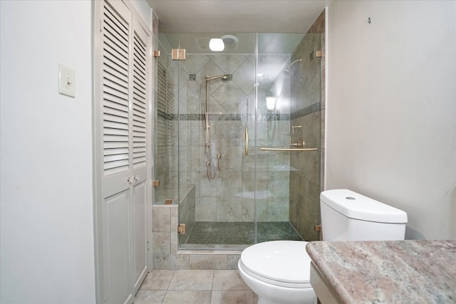 bathroom featuring tile patterned floors, toilet, a shower with door, and vanity