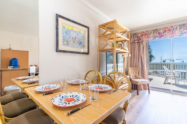 dining space featuring light hardwood / wood-style flooring, a wealth of natural light, and crown molding