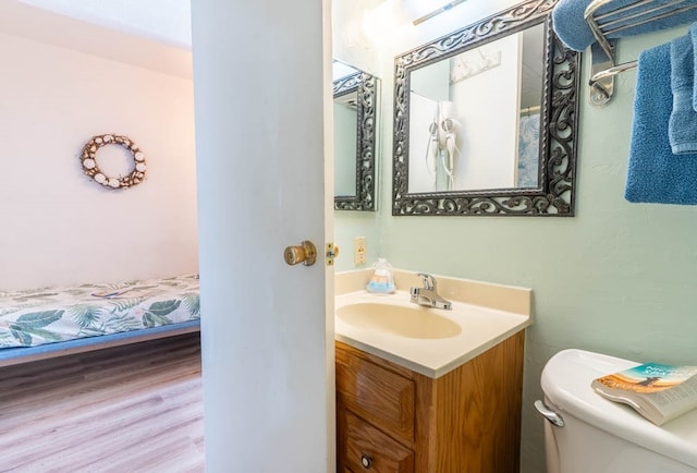 bathroom featuring wood-type flooring, vanity, and toilet