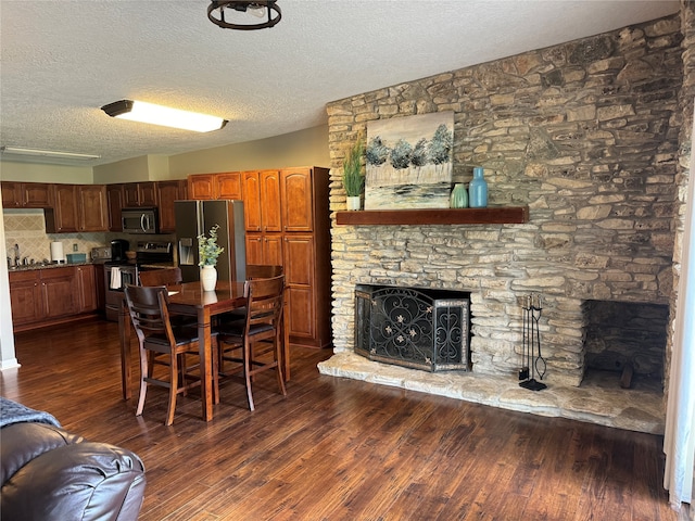 dining room with a fireplace, sink, dark wood-type flooring, and a textured ceiling